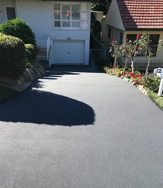 Seamless sloped grey concrete driveway leading up to residential garage in Newcastle